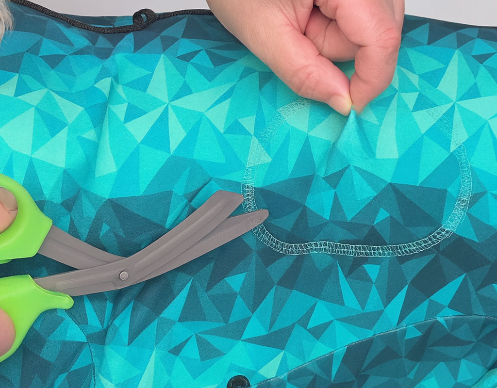 hands hold a turquoise geometric patterned fabric, pulling it taut
